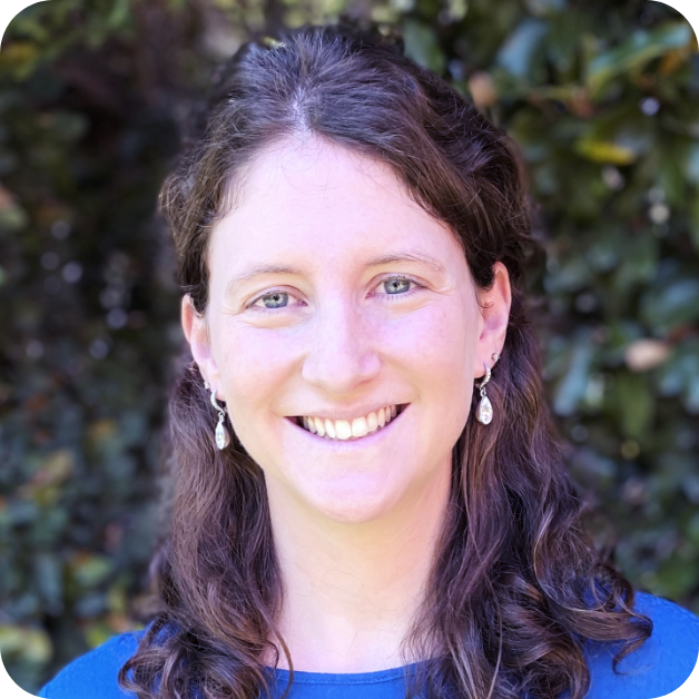 Headshot of woman smiling with nature background.