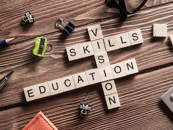 Scrabble tiles spelling education, skills, and vision on a wooden surface.
