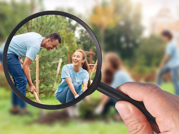 Magnifying glass focuses on two people gardening and laughing together.