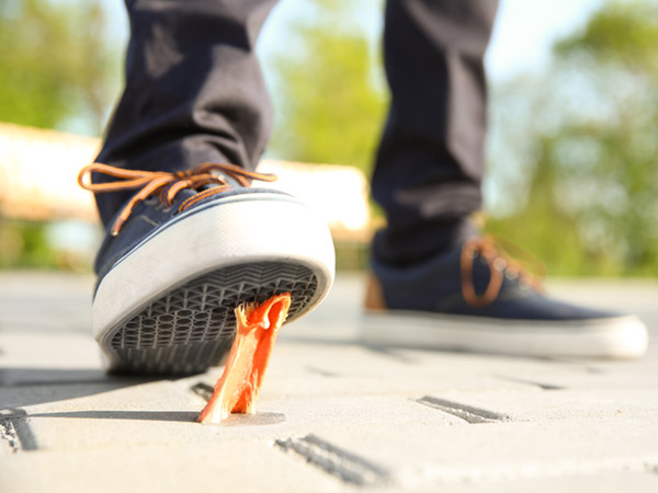 Shoe stepping on chewing gum on a sidewalk.