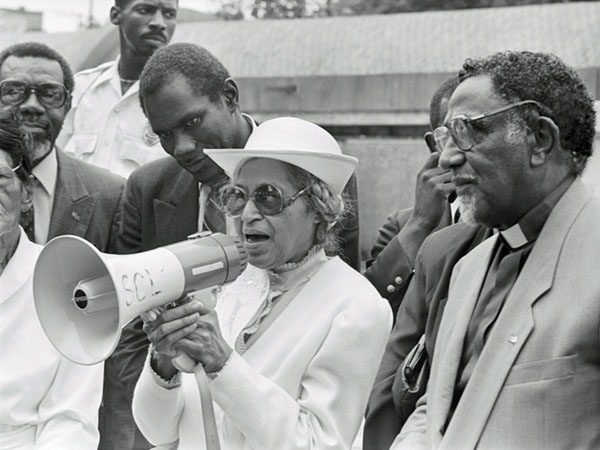 Black and white photo of woman speaking through megaphone at rally.