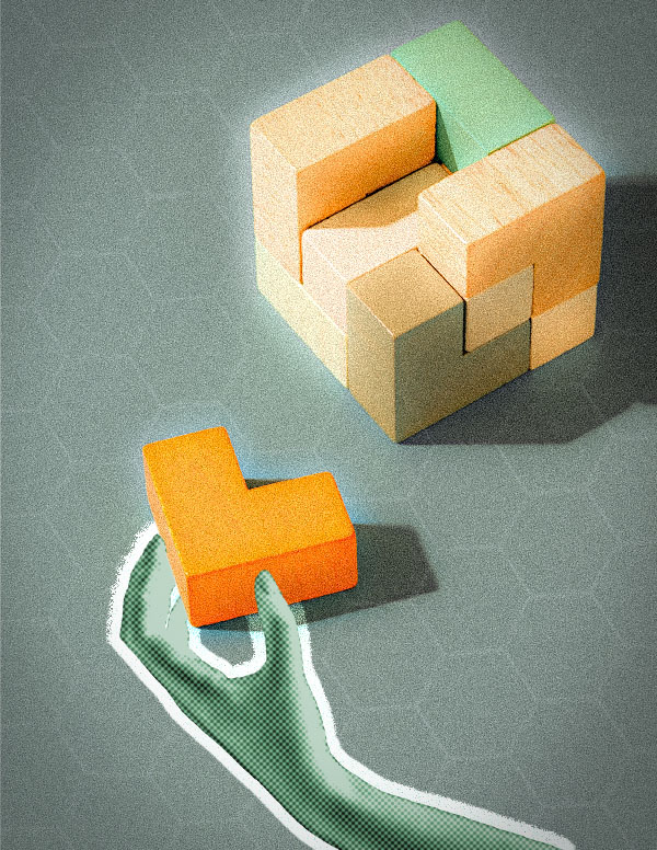 Hand holding puzzle piece near partially assembled wooden block structure.