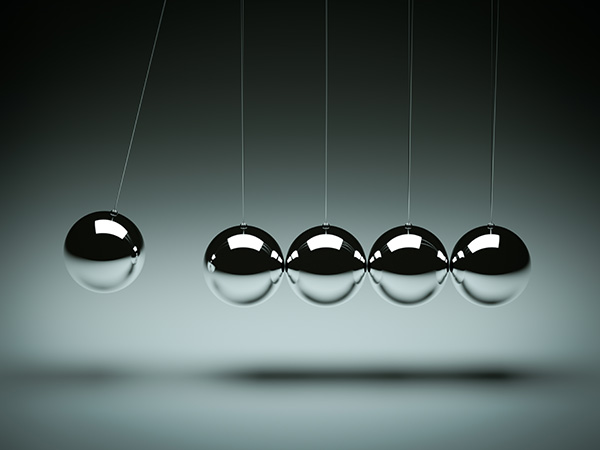 Five metallic spheres suspended in line against gray background.