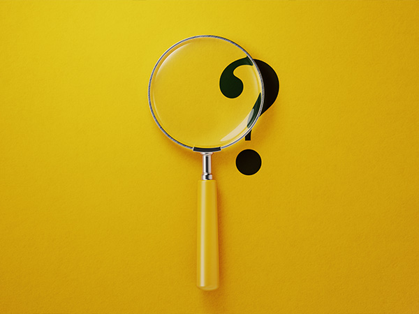 Magnifying glass over question mark on bright yellow background.