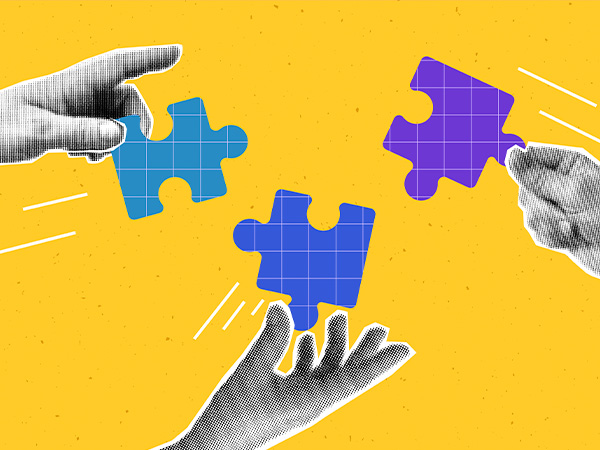 Hands arranging colorful puzzle pieces on yellow background.