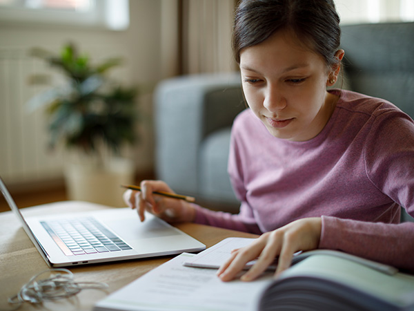 Young woman studying with laptop and books at desk.