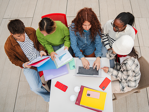 Group of students studying together with laptop and books.