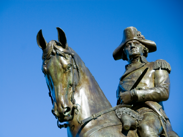 Bronze equestrian statue of George Washington against blue sky.