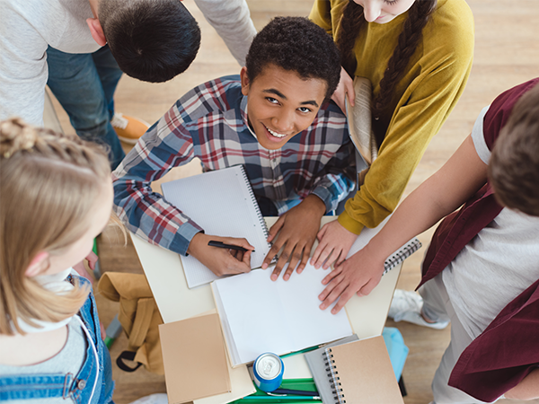 Smiling student surrounded by classmates during group study session.