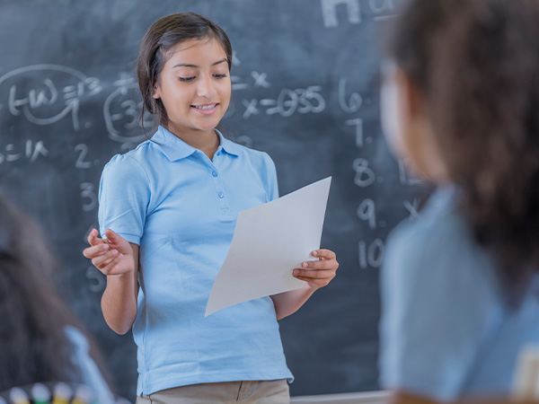 Student reading paper in front of chalkboard.