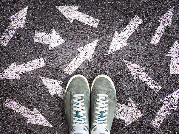 Feet in green sneakers surrounded by white arrows on asphalt.