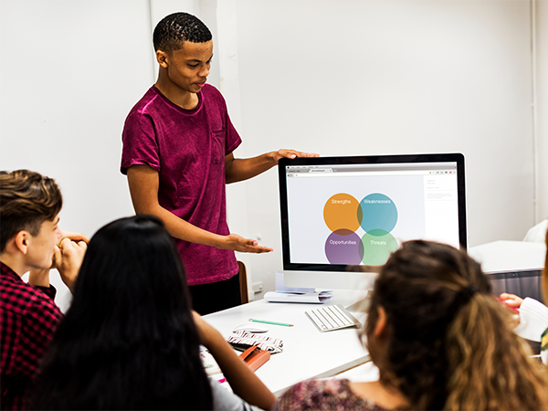 Student presenting diagram on computer screen to classmates.