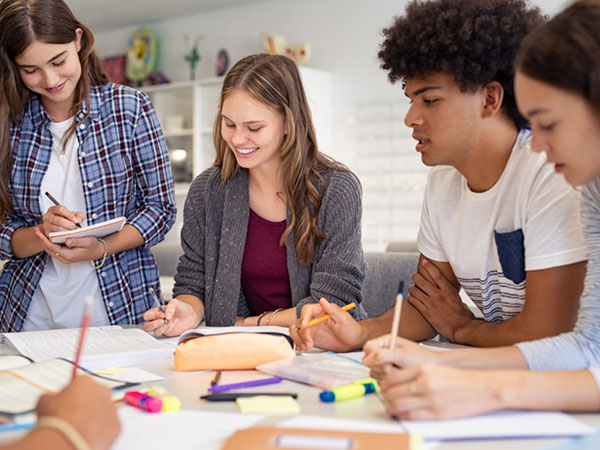 Students working together around a table with notebooks.