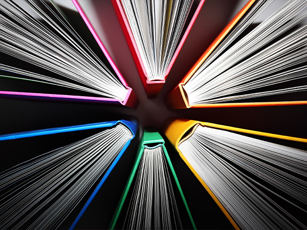 Colorful book spines form a circular pattern, pages fanning outward.