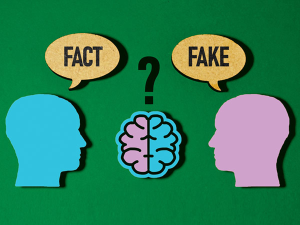 Two heads with speech bubbles saying "FACT" and "FAKE" above a brain.