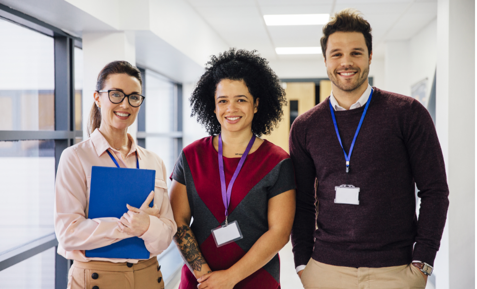 Three smiling professionals standing together in an office.